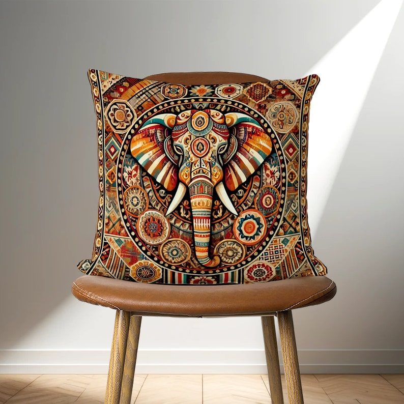 May include: A decorative throw pillow with a colorful, intricate design featuring an elephant's head in the center. The elephant is surrounded by geometric patterns and floral motifs in shades of orange, red, blue, and green.