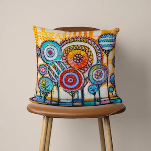May include: A colorful throw pillow with a whimsical design of trees with colorful circles as leaves. The background is a yellow and white striped pattern.