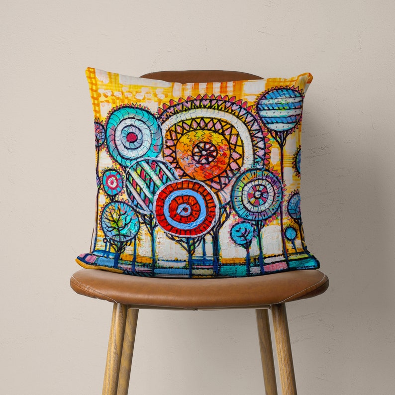 May include: A colorful throw pillow with a whimsical design of trees with colorful circles as leaves. The background is a yellow and white striped pattern.