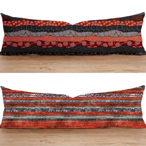 May include: Two decorative throw pillows with a red, black, and white geometric pattern. The pillows are on a wooden surface.