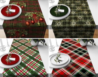 May include: Four different Christmas table runner designs. The first runner is red and green plaid with a Christmas ornament and holly sprig design. The second runner is green and white plaid with a snowflake design. The third runner is red, green, and white plaid. The fourth runner is red and black plaid with a white and green plaid design.