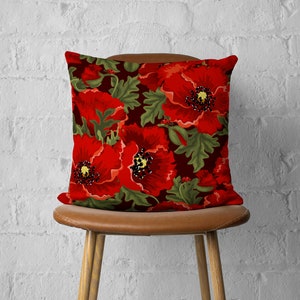 Puede incluir: Funda de coj&iacute;n roja con estampado de amapolas sobre fondo verde oscuro. La funda de coj&iacute;n presenta un patr&oacute;n floral con amapolas rojas y hojas verdes.