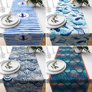 May include: Four different table runners with nautical themes. The first runner has blue and white stripes with anchors and a watercolour effect. The second runner has a blue and white pattern with fish and seashells. The third runner has a blue and white pattern with seashells. The fourth runner has a blue and white pattern with jellyfish.