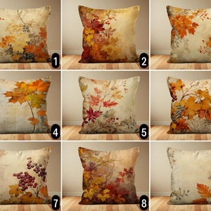 Può includere: Nove diverse fodere per cuscini con motivi di foglie autunnali. I cuscini presentano una varietà di colori autunnali, tra cui rosso, arancione, giallo e marrone. I motivi sono stampati su un tessuto beige simile al lino.