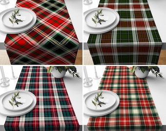 May include: Four red and green plaid table runners with white accents. The runners are made of a woven fabric and have a classic plaid pattern.