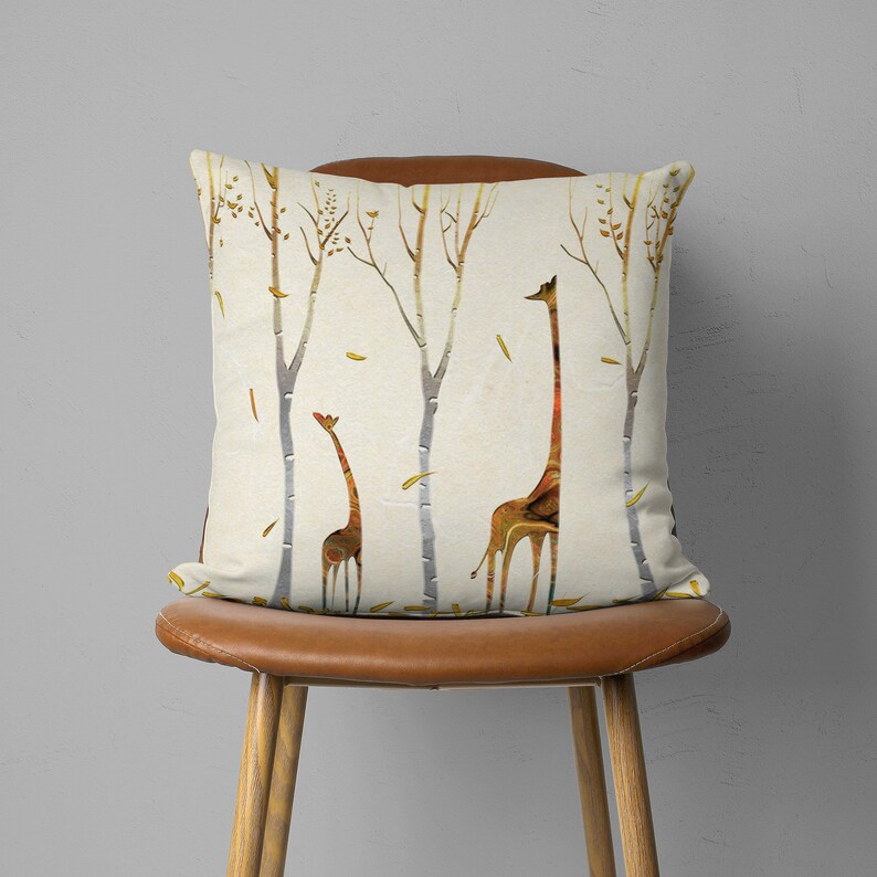 May include: A throw pillow with a cream background and a pattern of brown giraffes and trees. The giraffes are silhouetted against a white background and have a textured, marbled appearance.