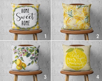 Peut inclure: Quatre designs différents d'oreillers décoratifs avec des citrons et du texte sur le thème du citron. Les oreillers sont tous blancs avec des accents jaunes. Le premier oreiller a un fond à carreaux jaunes et blancs avec le texte "Home Sweet Home" dans une couronne noire. Le deuxième oreiller a un motif de citron jaune et blanc. Le troisième oreiller a une branche de citron avec des feuilles vertes et des fleurs blanches. Le quatrième oreiller a un gros citron jaune avec le texte "If life gives you lemons make a lemonade" en blanc.