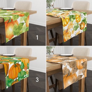 Pode incluir: Quatro caminhos de mesa com desenhos de abóboras e folhas são exibidos em mesas de madeira. Os caminhos de mesa apresentam ilustrações em aquarela de abóboras laranja e folhas verdes sobre fundos brancos. Cada caminho de mesa tem uma paleta de cores e um padrão únicos.
