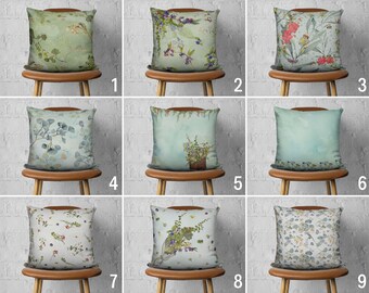 May include: Nine different pillow covers with floral and botanical patterns on a light blue background. The pillows are displayed on wooden chairs against a white brick wall.