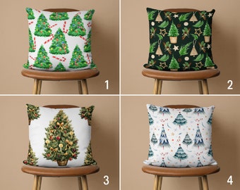 May include: Four different Christmas pillow designs. The first pillow has a white background with green Christmas trees and red candy canes. The second pillow has a dark green background with green Christmas trees, gold stars, and white ornaments. The third pillow has a white background with a single green Christmas tree with gold ornaments and red berries. The fourth pillow has a white background with blue and green Christmas trees with white stars and red berries.