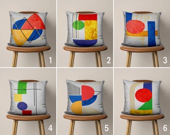 May include: Six different geometric patterned throw pillows on chairs. The pillows are white with colorful geometric shapes and lines. The pillows are arranged in a row on chairs with wooden legs.