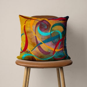 May include: A decorative throw pillow with an abstract design featuring swirling lines in shades of yellow, red, blue, and purple on a brown background.