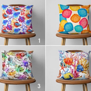 May include: Four different pillow designs with various watercolour patterns. The first pillow features a blue and pink fish pattern. The second pillow features a colourful seashell pattern. The third pillow features a colourful underwater scene with fish and coral. The fourth pillow features a colourful underwater scene with fish and coral.