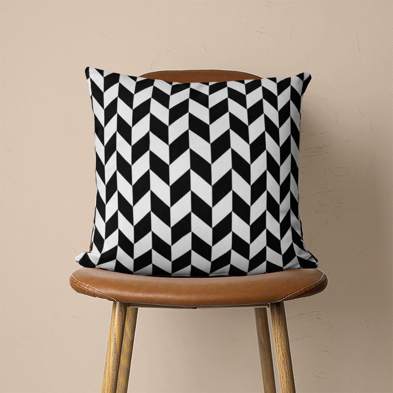May include: Black and white chevron patterned throw pillow on a brown chair.