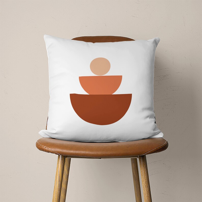 Pu&ograve; includere: Cuscino bianco con un design geometrico di tre semicerchi impilati in tonalit&agrave; arancio e marrone.