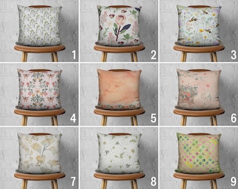 May include: Nine different pillow covers with various floral and abstract patterns. The pillow covers are displayed on wooden chairs against a white brick wall.