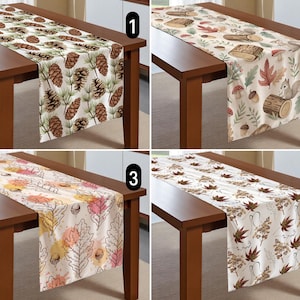 May include: Four table runners with autumn-themed designs. One features pine cones, another has a woodland scene with a squirrel, a third displays leaves and acorns, and the last showcases fall foliage.