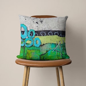 May include: A decorative cushion with an abstract design featuring blue circles, green and yellow stripes, and a white background.