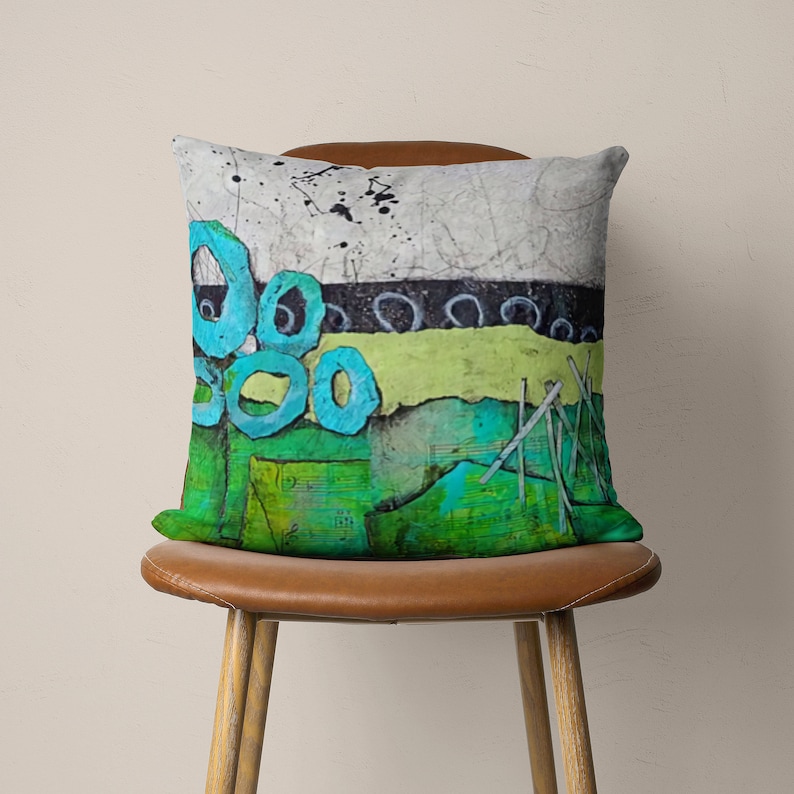 May include: A decorative cushion with an abstract design featuring blue circles, green and yellow stripes, and a white background.