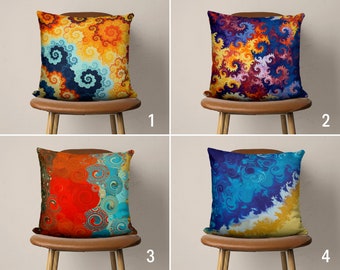 May include: Four decorative throw pillows with abstract patterns in shades of blue, orange, yellow, and red. The pillows are displayed on brown wooden chairs with a white background.