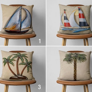 May include: Four decorative throw pillows with different designs. The first pillow features a blue and white sailboat with a red stripe. The second pillow features two sailboats with red and blue stripes. The third pillow features three palm trees with green leaves and brown trunks. The fourth pillow features a single palm tree with green leaves and a brown trunk.