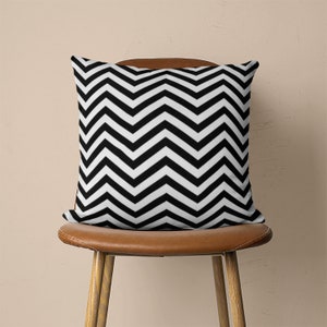 May include: A black and white chevron patterned throw pillow on a brown leather chair.