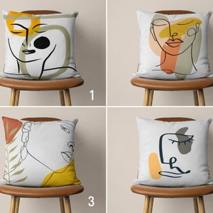Peut inclure: Quatre coussins décoratifs avec des motifs d'art abstrait en lignes représentant des visages et des formes géométriques en jaune, orange et marron sur fond blanc.