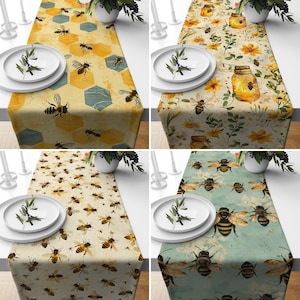 May include: Four table runners with different bee-themed designs. The first runner features a yellow and brown honeycomb pattern with bees. The second runner has a floral pattern with bees and jars of honey. The third runner has a light brown background with bees and a honeycomb pattern. The fourth runner has a blue-green background with bees and a honeycomb pattern.