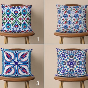 May include: Four decorative throw pillows with different patterns inspired by traditional Turkish tile designs. The pillows are white with blue, red, and green accents. The pillows are displayed on brown chairs with a light brown background.