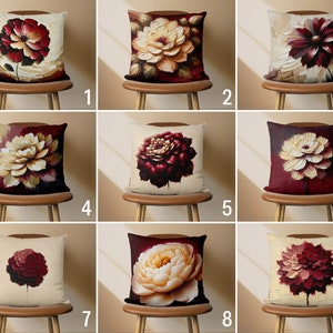 Pode incluir: Nove designs diferentes de almofadas decorativas com vários padrões florais. Cada almofada tem um fundo creme com uma grande flor colorida no centro. As flores são pintadas em tons de vermelho, bordô e creme.