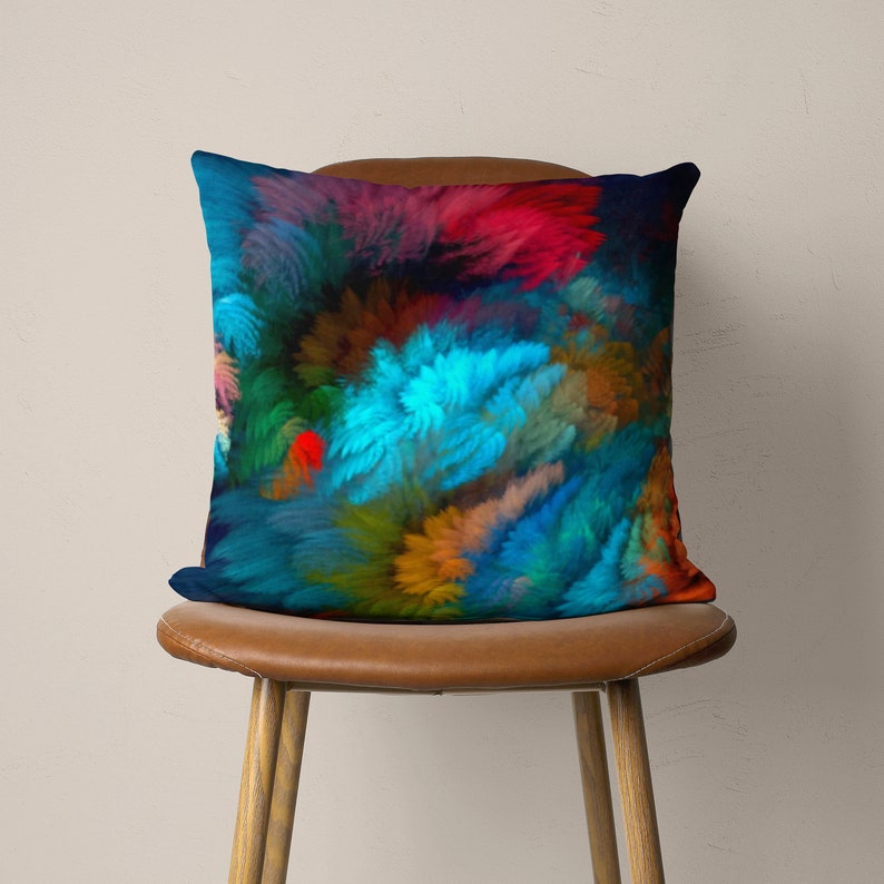 May include: A colorful throw pillow with a blue, red, green, and brown abstract design. The pillow is sitting on a brown leather chair.