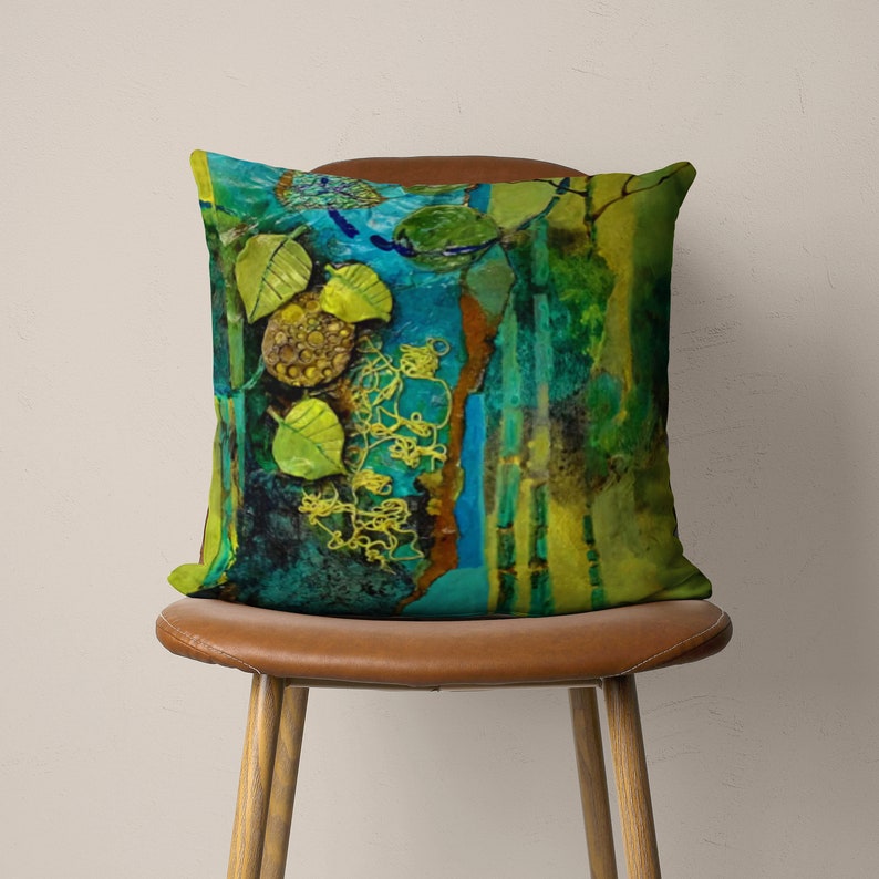 May include: A decorative cushion with an abstract design featuring green, blue and yellow colours. The cushion has a textured surface and a unique, artistic pattern.