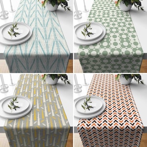 Può includere: Quattro diversi runner da tavolo con motivi geometrici. I runner sono in blu e bianco, verde e bianco, arancione e nero e giallo e grigio.