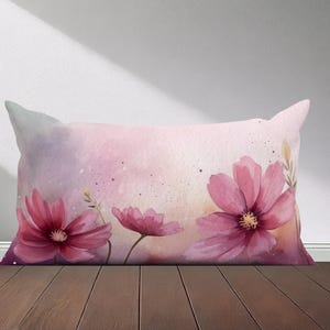 Peut inclure: Un oreiller rose et violet avec un motif aquarelle de fleurs roses. Les fleurs ont un aspect doux et d&eacute;lav&eacute; et sont dispos&eacute;es dans un motif l&acirc;che et fluide.