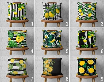 May include: Nine different pillow designs featuring lemons and other fruit on a black and white striped background, a black background with green leaves, or a plaid background. The pillows are displayed on wooden chairs against a white brick wall.