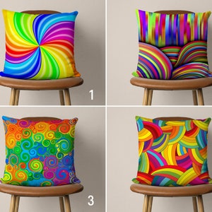 May include: Four colourful throw pillows with different geometric patterns. The pillows are arranged on four wooden chairs with brown cushions. The pillows are all made of fabric and have a variety of colours, including red, orange, yellow, green, blue, and purple.