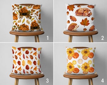 May include: Four different pillow designs with autumnal themes. The first pillow features a brown wagon with pumpkins and fall leaves. The second pillow has a sleeping deer and a hedgehog with fall leaves. The third pillow has a pattern of fall leaves. The fourth pillow has a pattern of sunflowers and lemons.