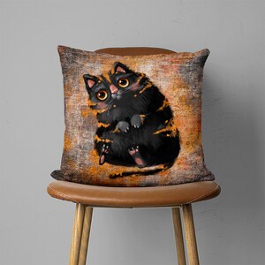 May include: A black and orange cat with big eyes sits on a brown and orange patterned pillow. The pillow is on a brown chair.