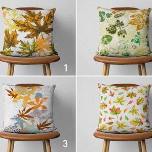 May include: Four different pillow designs featuring various leaf patterns. The pillows are displayed on brown chairs with white backgrounds. The designs include yellow, orange, green, and red leaves.
