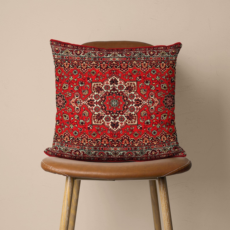 May include: Red cushion with a traditional Persian rug pattern. The cushion is sitting on a brown leather chair.