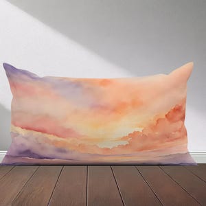 Peut inclure: Un coussin rectangulaire avec une peinture aquarelle d'un ciel de coucher de soleil. Le ciel est un m&eacute;lange de teintes orange, rose et violette avec des nuages blancs moelleux.