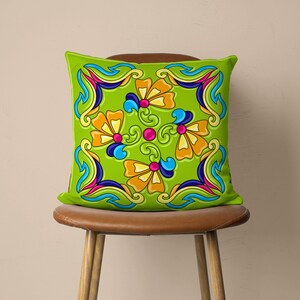 May include: A green cushion with a colourful floral pattern. The cushion features a repeating design of stylised flowers with blue, yellow, pink, and orange accents.