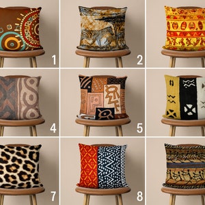 May include: Nine different throw pillow designs featuring various African-inspired patterns and colors. The pillows are displayed on brown wooden chairs.