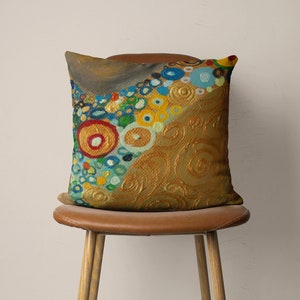 Puede incluir: Una almohada decorativa con un dise&ntilde;o abstracto colorido que presenta c&iacute;rculos, remolinos y puntos en tonos de amarillo, azul, verde, rojo y dorado. La almohada est&aacute; sentada en una silla de cuero marr&oacute;n.