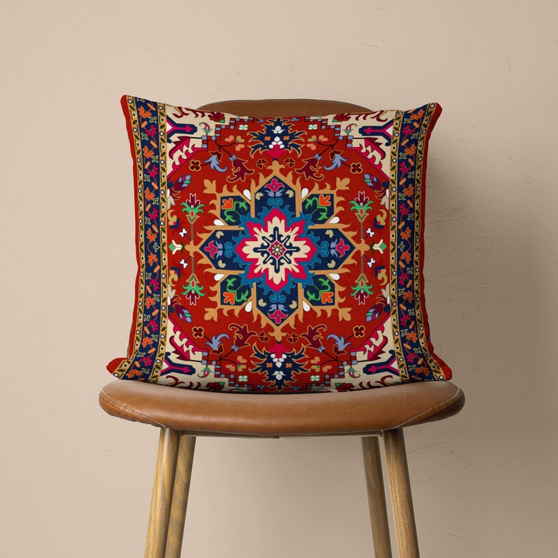 May include: A red, white and blue patterned cushion with a geometric design. The cushion is sitting on a brown leather chair.