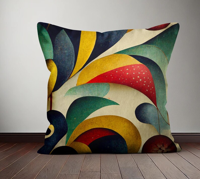 Op de afbeelding: Een decoratief kussen met een geometrisch patroon met abstracte vormen in tinten rood, geel, blauw en groen. Het kussen heeft een cr&egrave;mekleurige achtergrond.