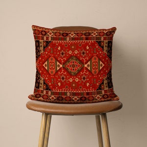 May include: Red, black and green patterned throw pillow with a geometric design. The pillow is sitting on a brown leather chair.