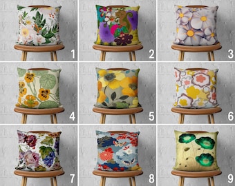 May include: Nine different floral patterned throw pillow covers displayed on chairs. The pillows are all square and feature a variety of floral designs, including roses, daisies, and abstract patterns. The pillows are all in different colors, including pink, yellow, blue, green, and purple.