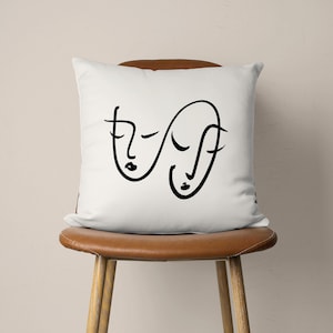 Puede incluir: Almohada blanca con un dibujo de l&iacute;nea negra de dos caras abstractas.