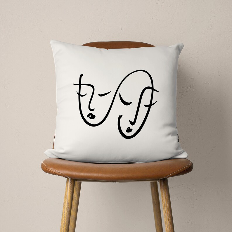 Puede incluir: Almohada blanca con un dibujo de l&iacute;nea negra de dos caras abstractas.